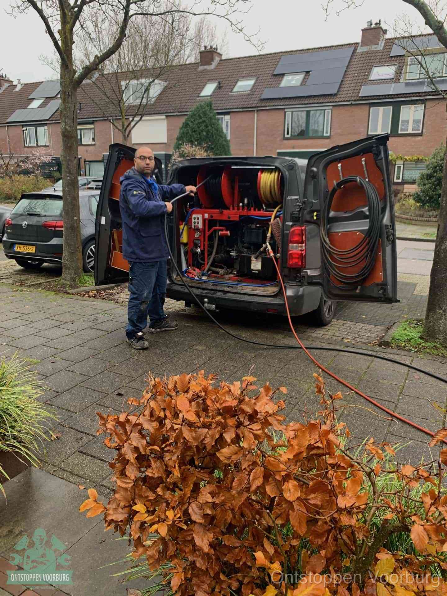 Monteur met rioolreinigingsbus levert rioolservice in de wijk in Voorburg