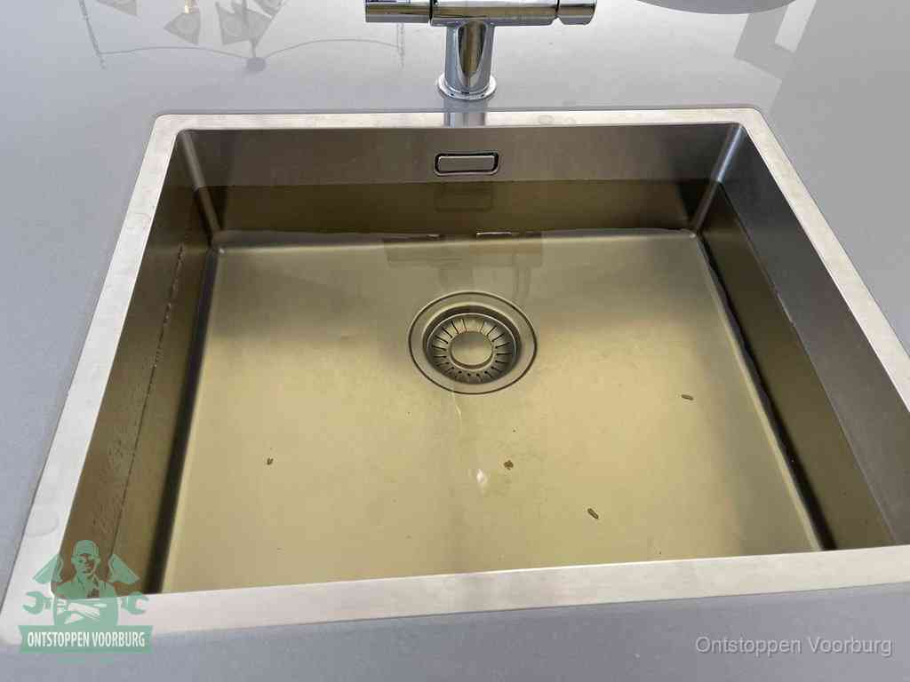 Stilstaand water in een rvs spoelbak dat niet wegloopt, een duidelijk signaal van een gootsteenverstopping in Voorburg