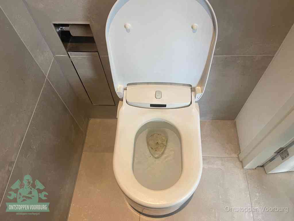 Een wit hangtoilet waarin een prop wc-papier op het water blijft drijven, een duidelijk signaal van een verstopte wc in Voorburg