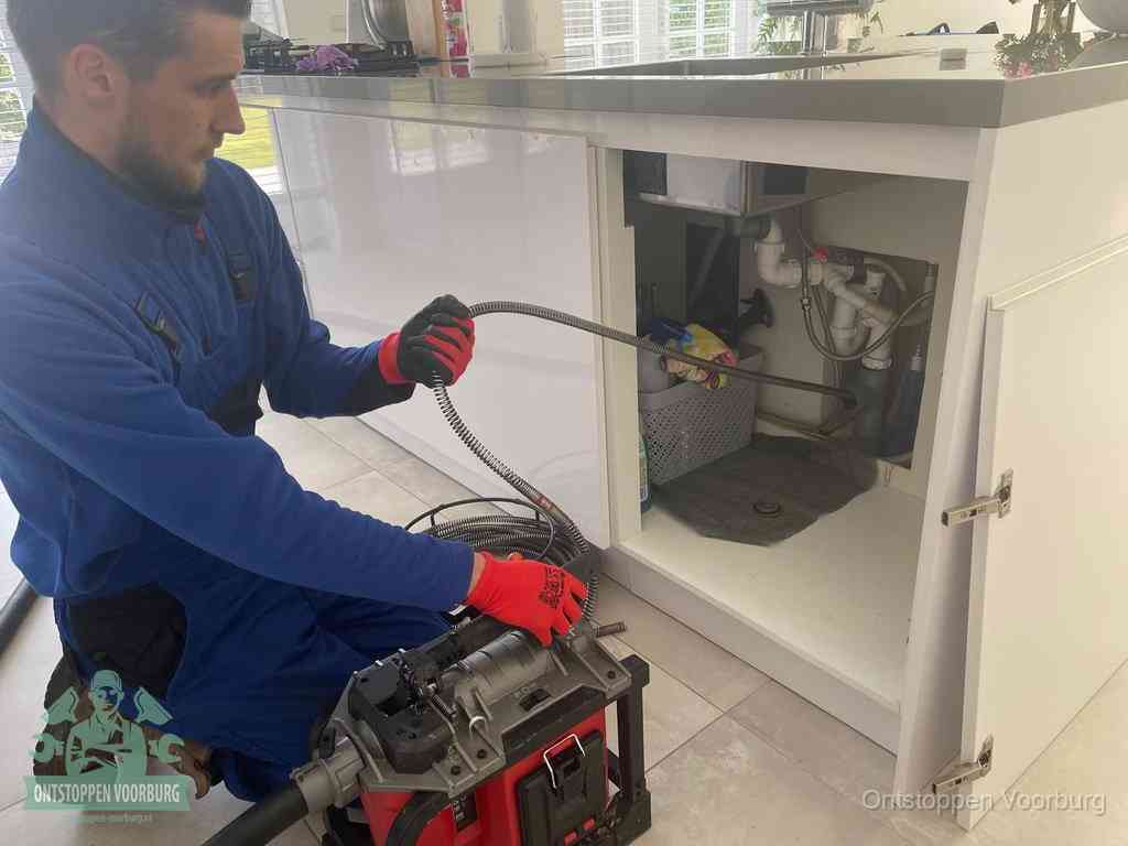 Een monteur reinigt de keukenafvoer grondig met een veermachine om terugkerende gootsteenverstoppingen te voorkomen in Voorburg