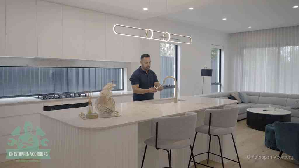 Een bewoner bij de keukenspoelbak die zelf aan de slag gaat met een verstopte gootsteen in Voorburg